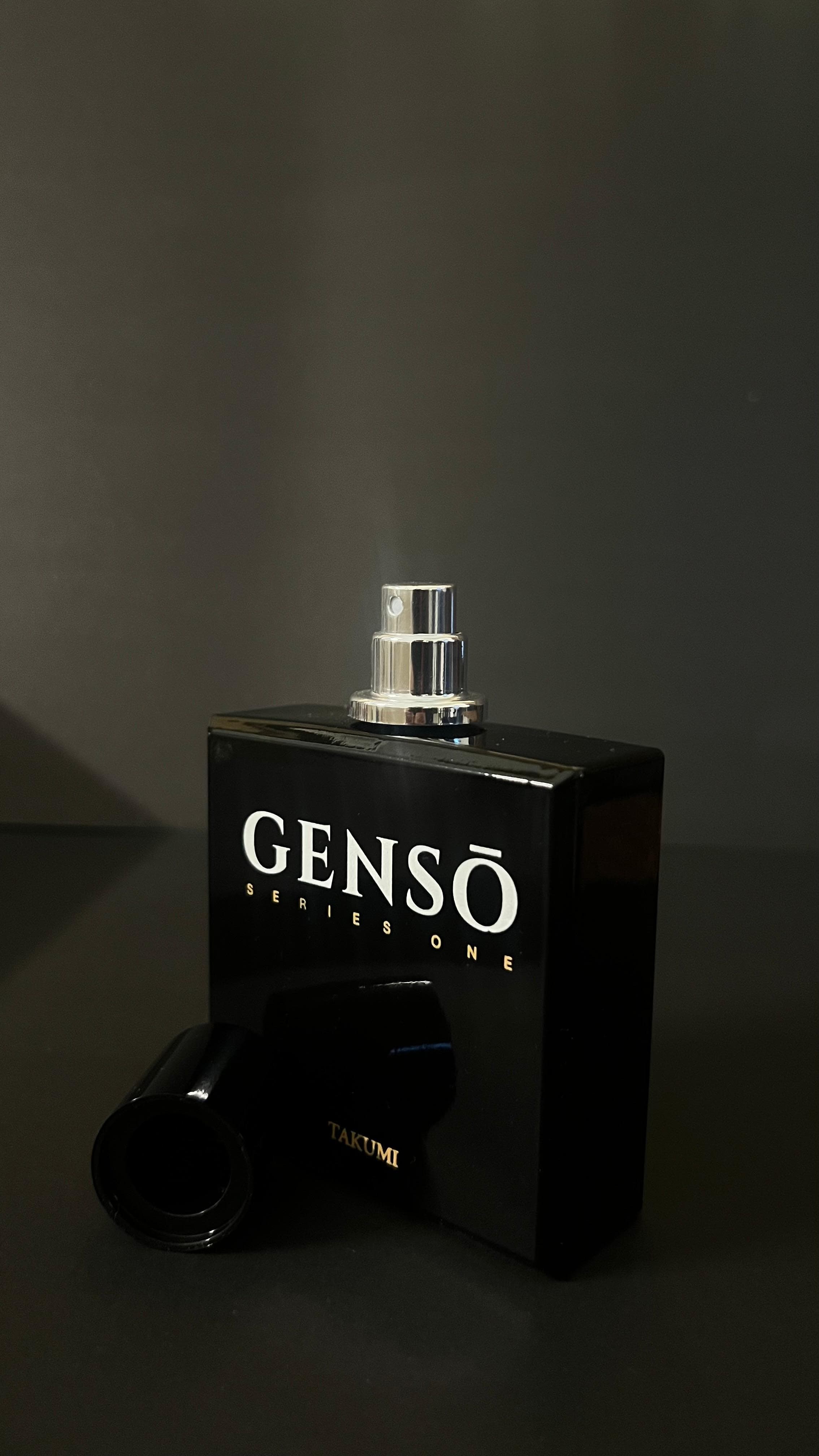 TAKUMI GENSŌ — macro of the gloss-black bottle and chrome atomizer against dark ground